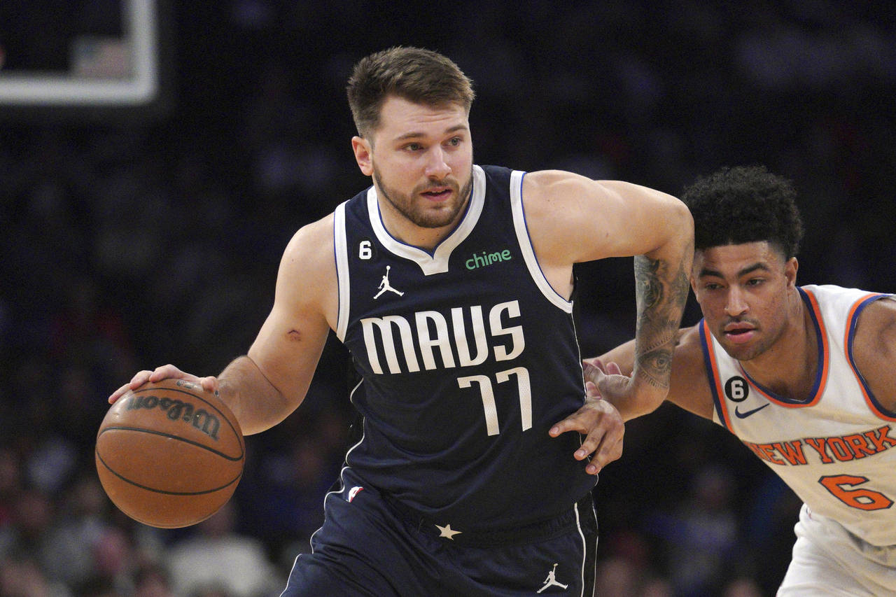 Dallas Mavericks guard Luka Doncic, left, drives the lane around New York Knicks guard Quentin Grim...