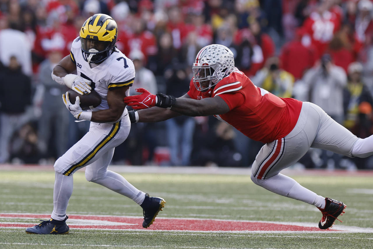 Michigan running back Donovan Edwards, left, turns up field past Ohio State defensive lineman Zach ...