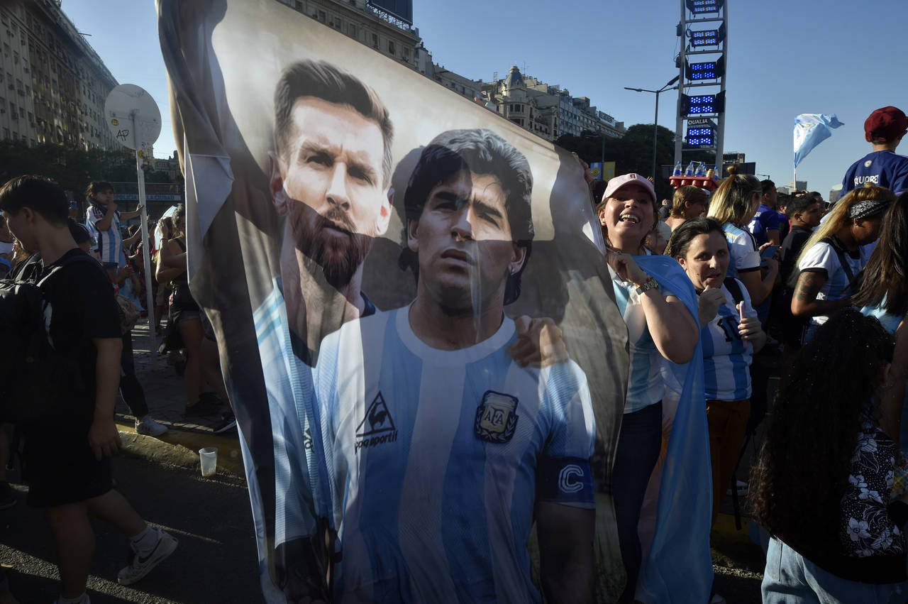 A flag featuring Lionel Messi, left, and the late soccer great Maradona hangs amid Argentina soccer...