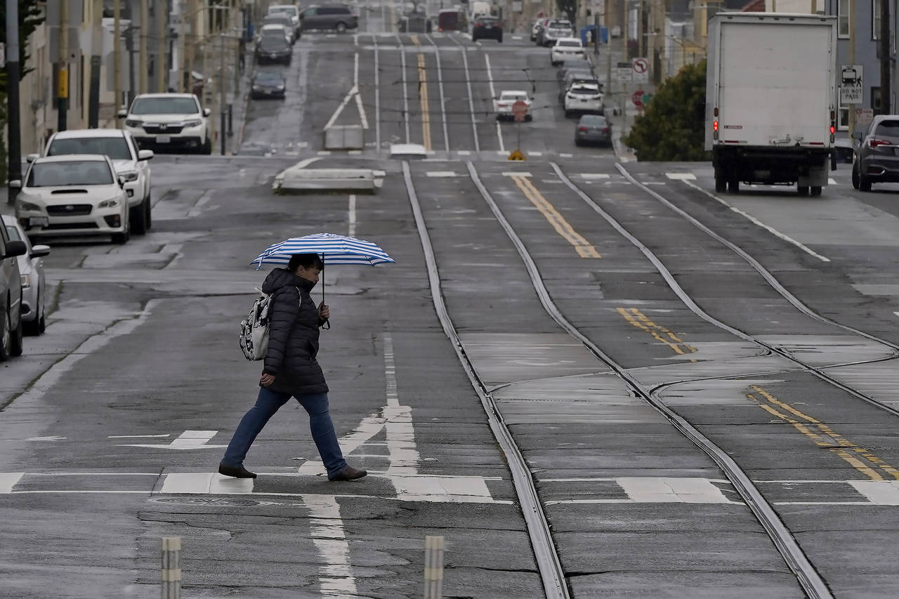 FILE - A pedestrian carries an umbrella while crossing a street in San Francisco, Thursday, April 1...