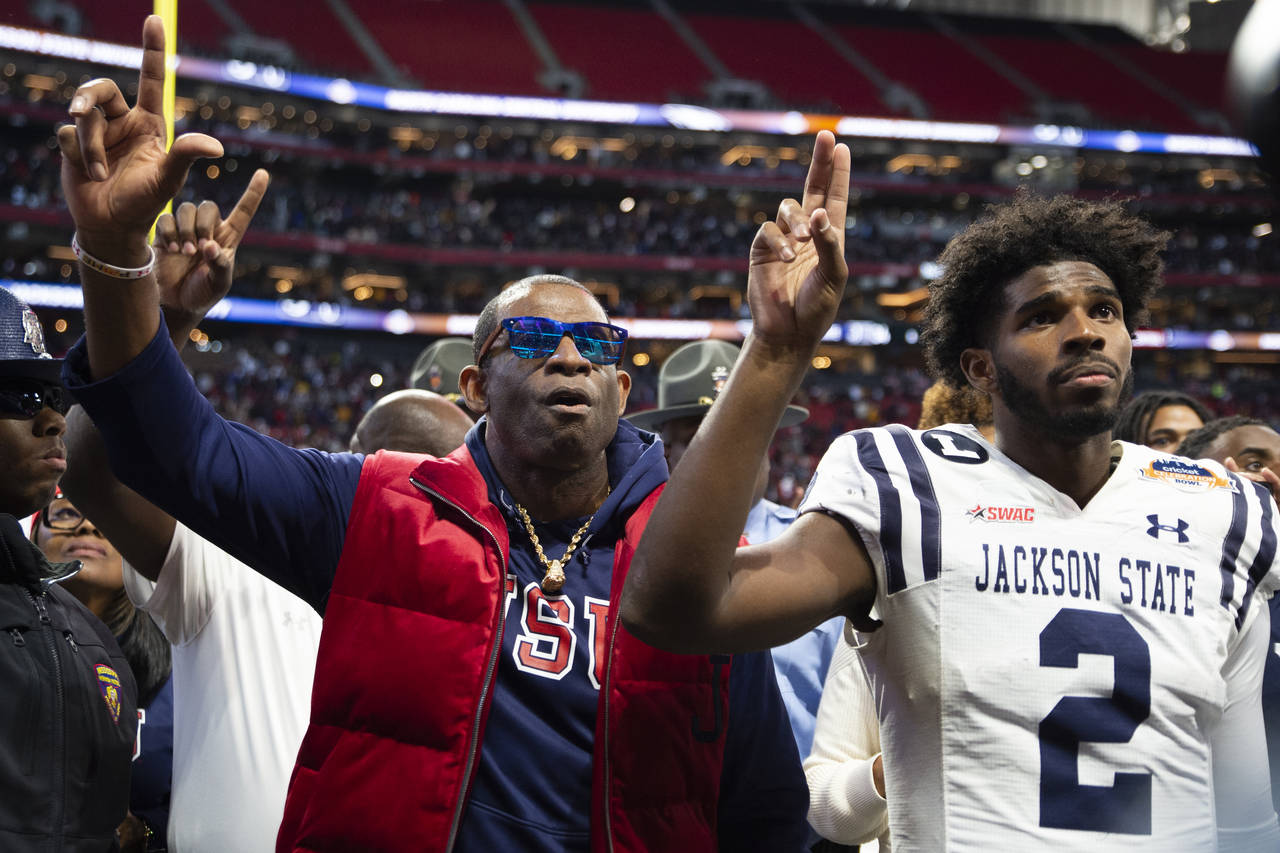 Jackson State head coach Deion Sanders, left, and his son quarterback Shedeur Sanders sing the scho...