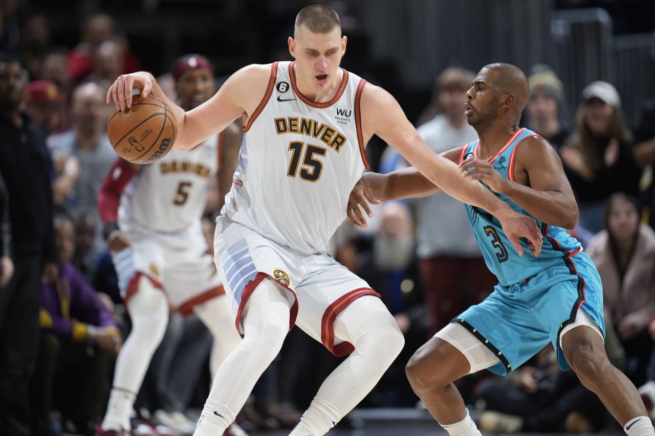 Denver Nuggets center Nikola Jokic, left, works the ball inside to the rim as Phoenix Suns guard Ch...
