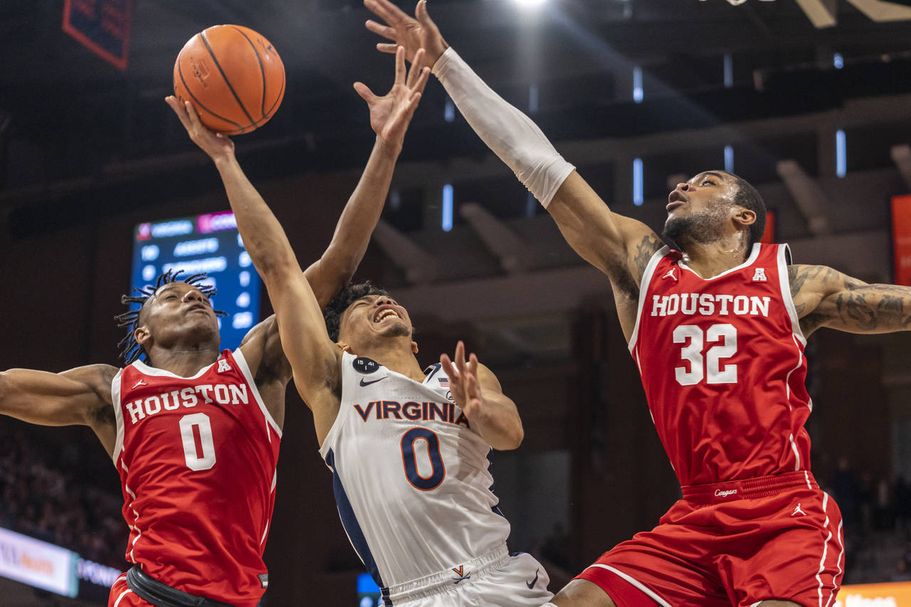Virginia guard Kihei Clark, center, is blocked by Houston guard Marcus Sasser, left, and forward Re...