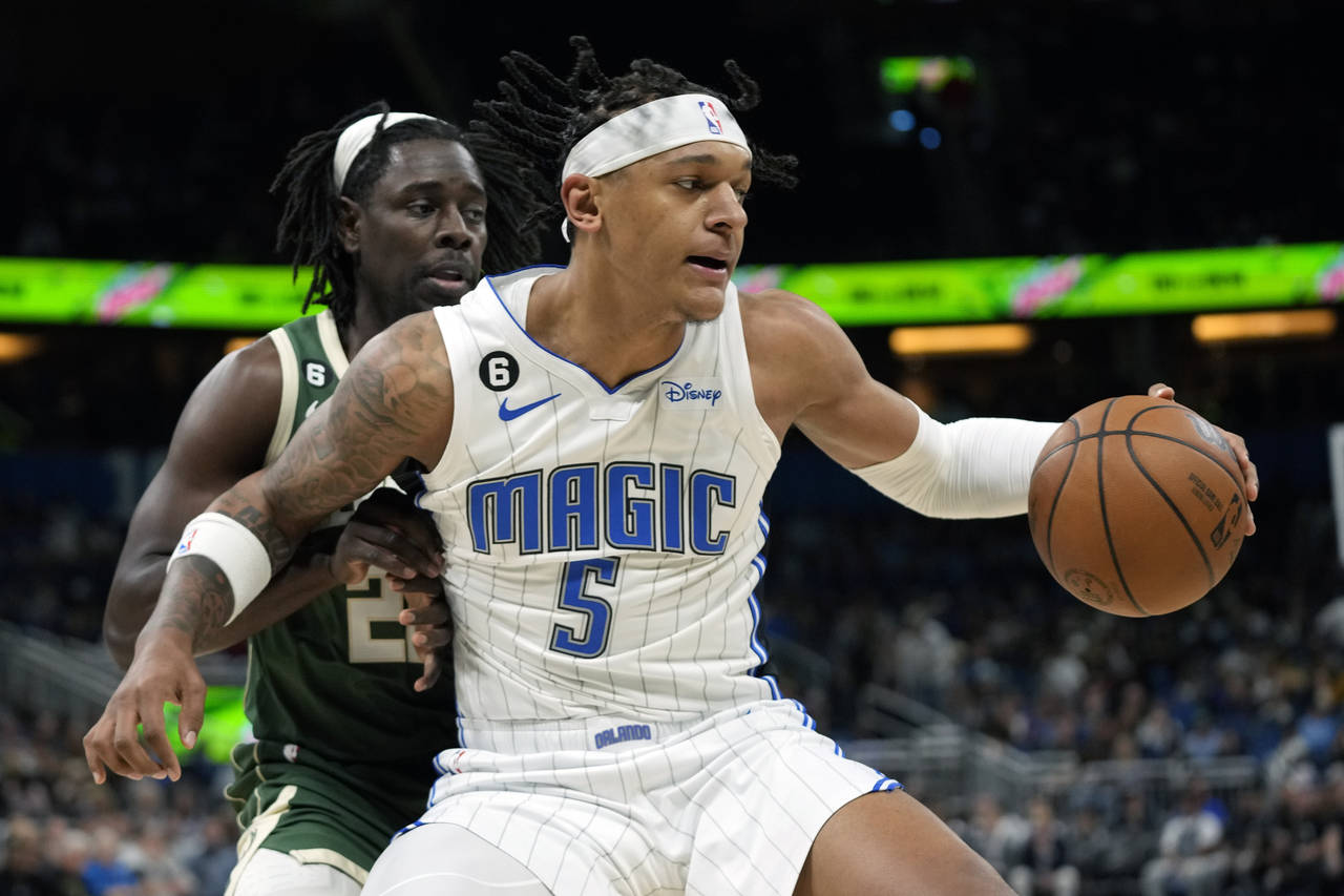 Orlando Magic's Paolo Banchero (5) looks to get around Milwaukee Bucks' Jrue Holiday, left, during ...