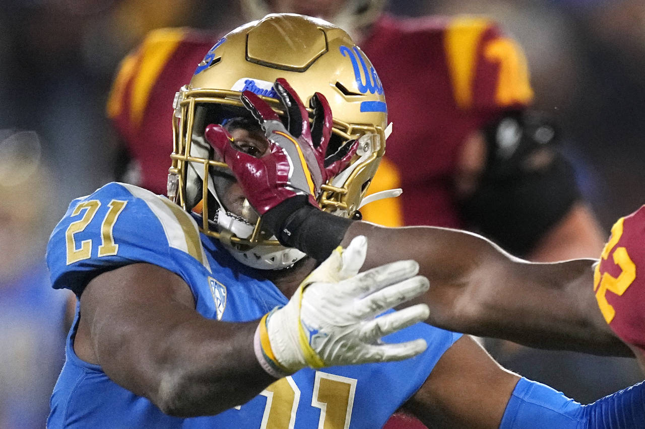 Southern California running back Darwin Barlow, right, fends off UCLA linebacker JonJon Vaughns dur...