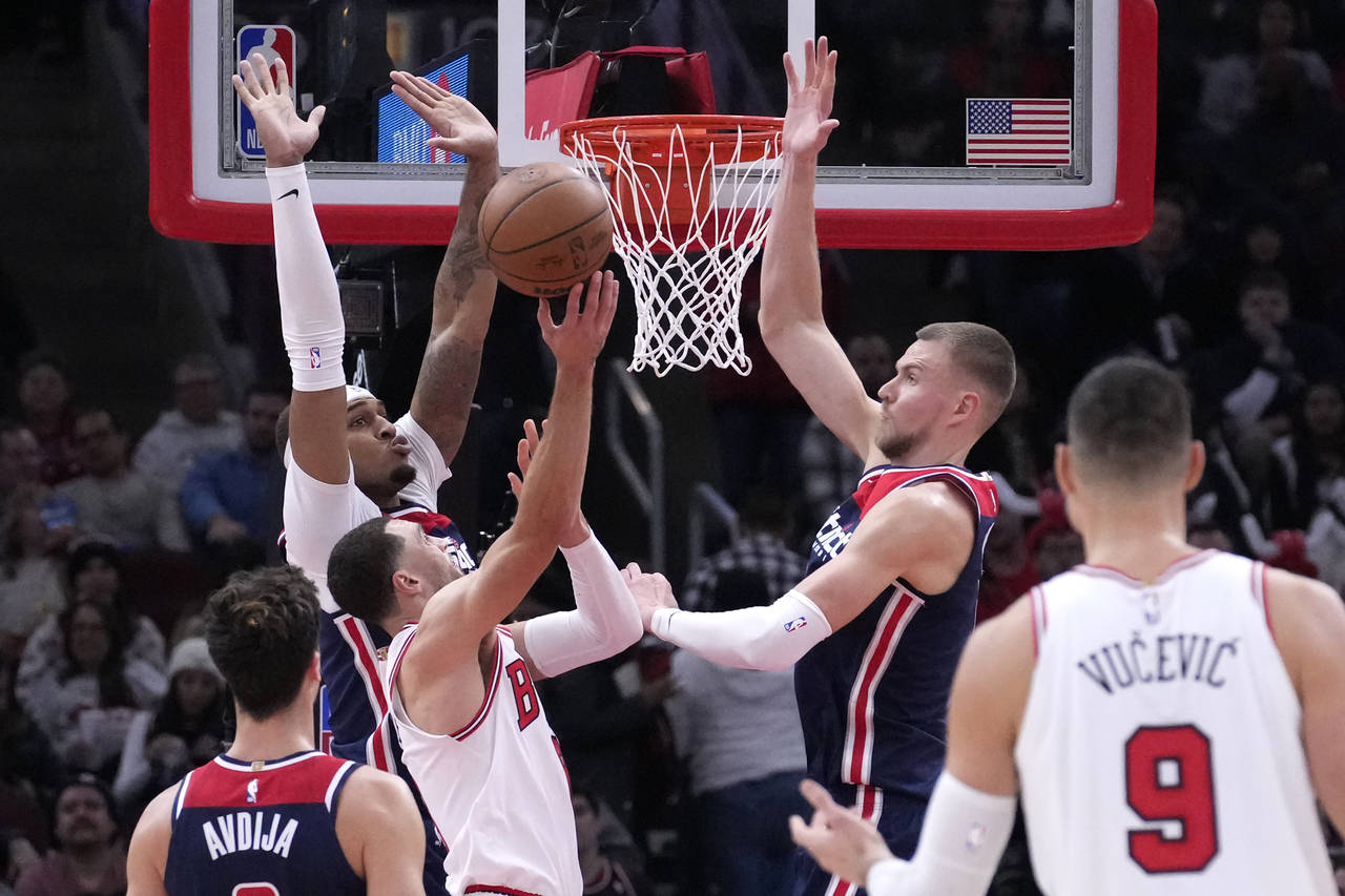 Chicago Bulls' Zach LaVine shorts between Washington Wizards' Daniel Gafford, left, and Kristaps Po...