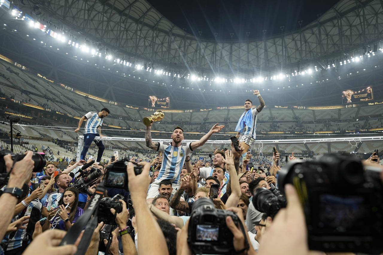 Argentina's Lionel Messi celebrates with the trophy in front of the fans after winning the World Cu...