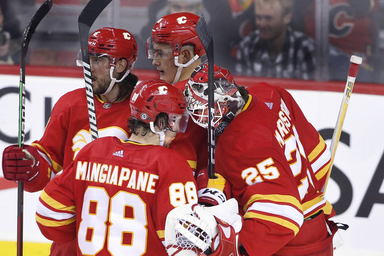 Calgary Flames goalie Jacob Markstron, right, and teammate Andrew Mangiapane (88) celebrate the tea...