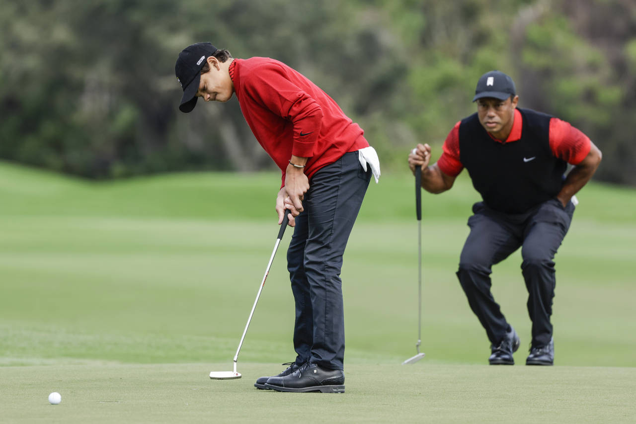 Charlie Woods, left, putts on the 2nd green while Tiger Woods, right, watches during the final roun...