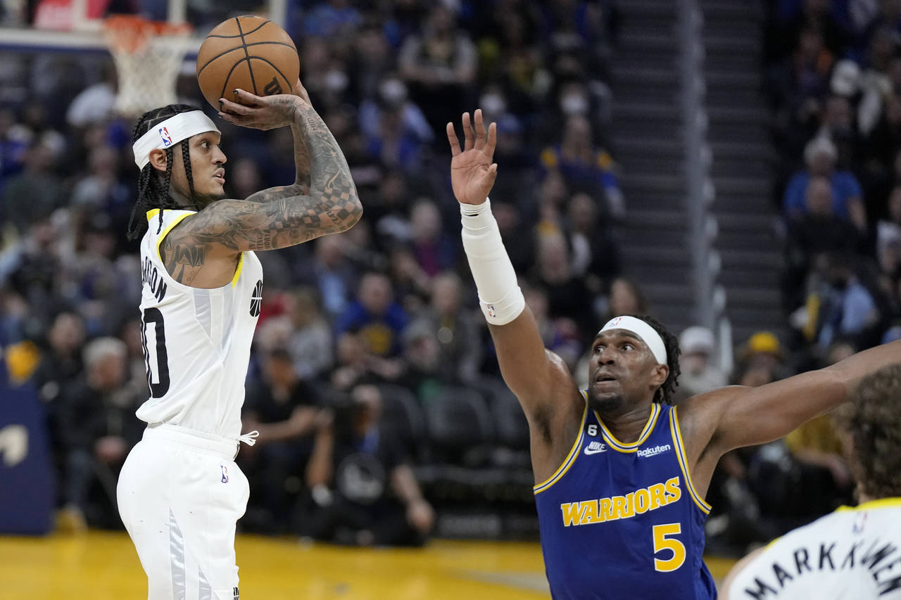 Utah Jazz guard Jordan Clarkson, left, makes a 3-point basket while being defended by Golden State ...