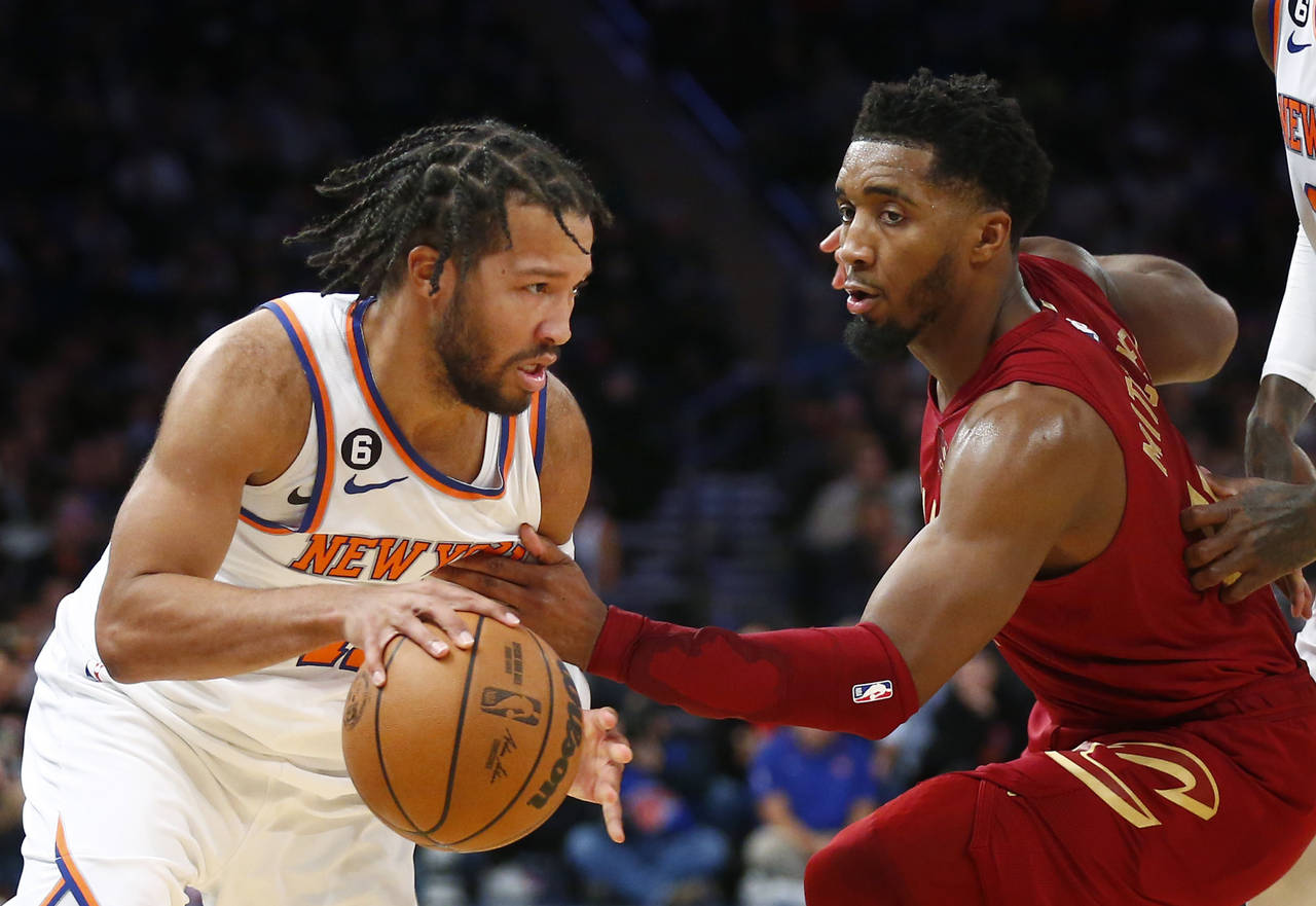 New York Knicks guard Jalen Brunson, left, dribbles around Cleveland Cavaliers guard Donovan Mitche...