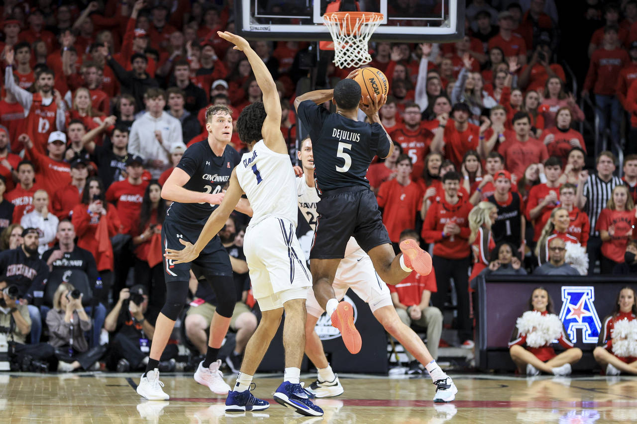 Cincinnati guard David DeJulius (5) goes up to shoot a 3-point basket as he is fouled by Xavier gua...