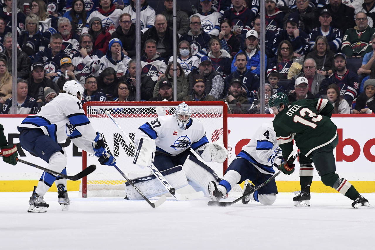 Minnesota Wild's Sam Steel (13) takes a shot on Winnipeg Jets goaltender Connor Hellebuyck (37) dur...