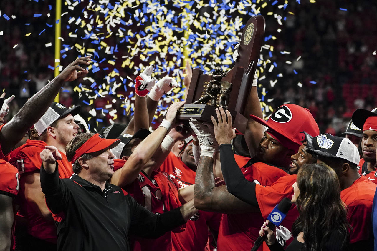 Georgia head coach Kirby Smart and defensive lineman Jalen Carter (88) hoist the trophy after defea...