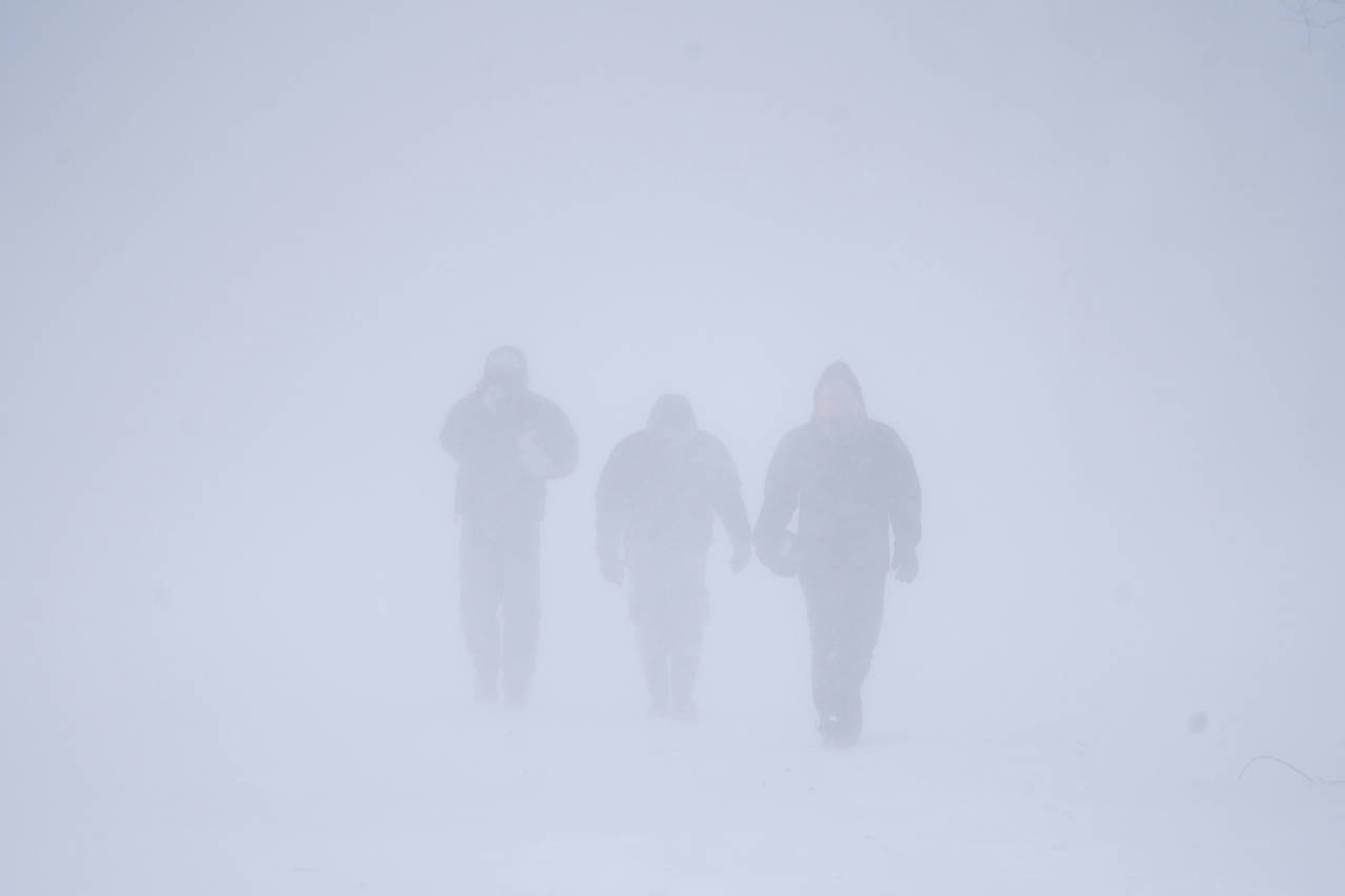 Three men walk down Richmond Avenue in whiteout conditions during a sustained blizzard in Buffalo, ...