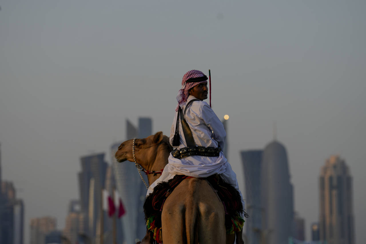 A guard rides his camels outside the Amiri Diwan in Doha, Sunday, Nov. 27, 2022. (AP Photo/Natacha ...
