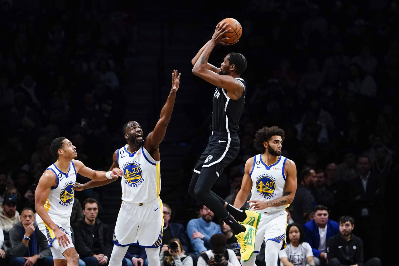 Golden State Warriors' Draymond Green (23) and Jordan Poole (3) defend a shot by Brooklyn Nets' Kev...