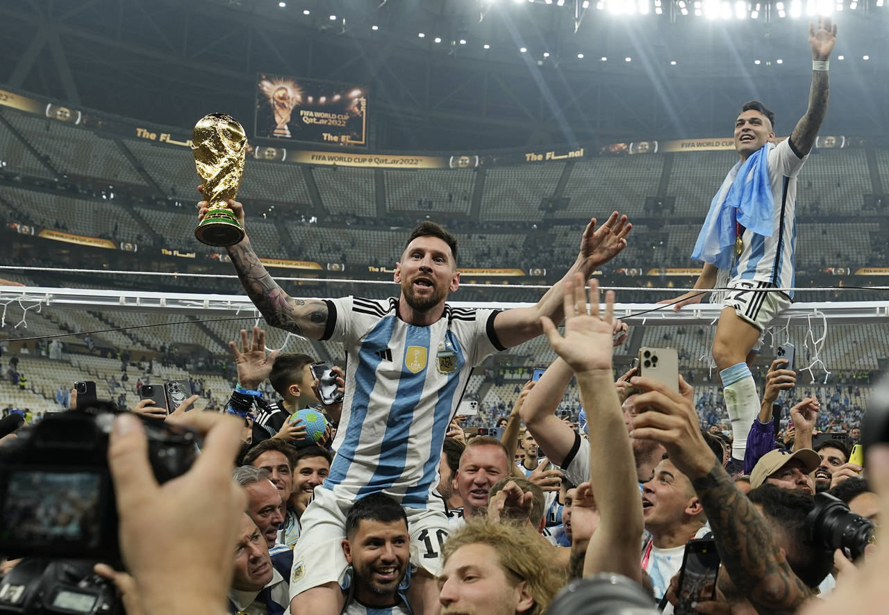 Argentina's Lionel Messi celebrates with the trophy in front of the fans after winning the World Cu...