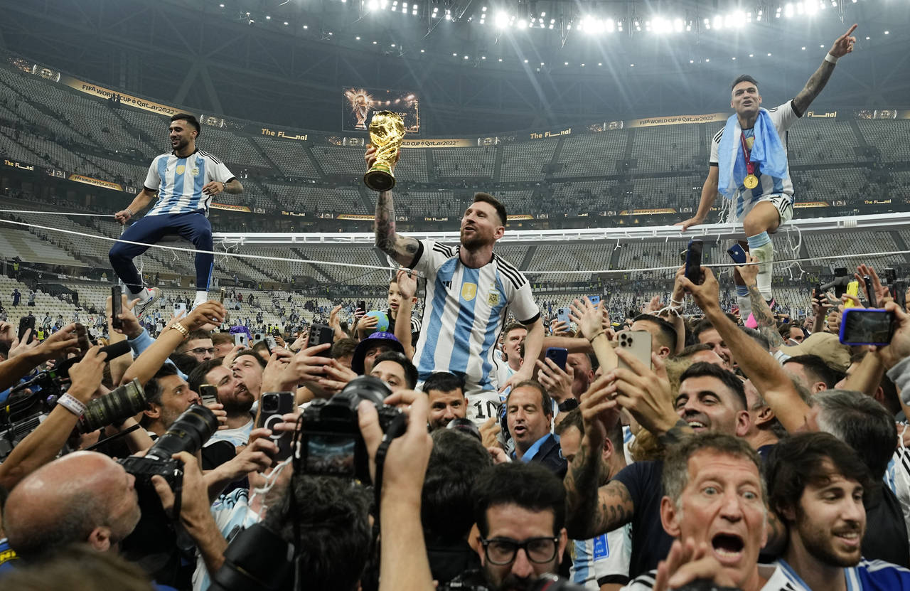 Argentina's Lionel Messi celebrates with the trophy in front of the fans after winning the World Cu...