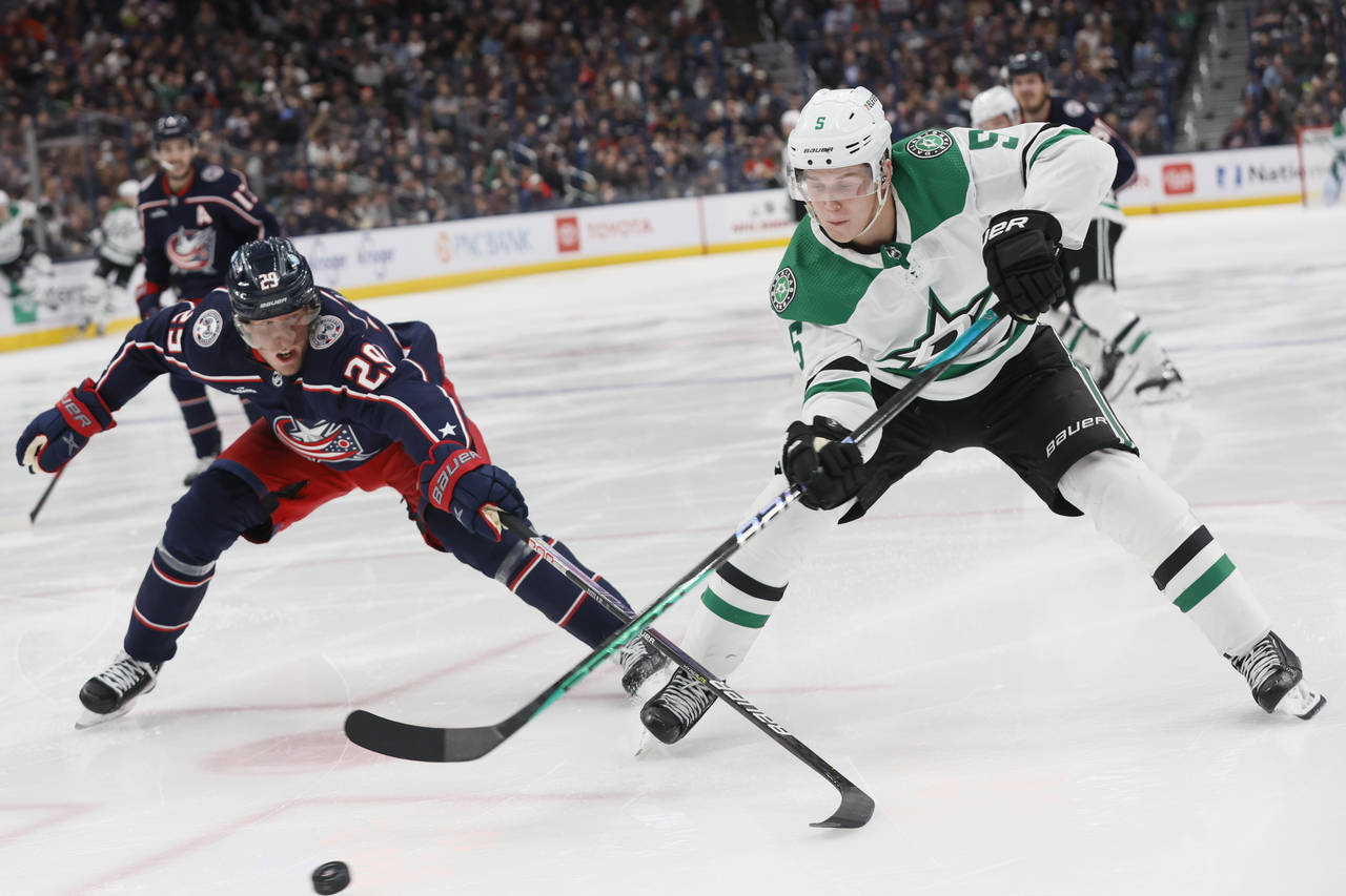 Dallas Stars' Nils Lundkvist, right, passes the puck past Columbus Blue Jackets' Patrik Laine durin...
