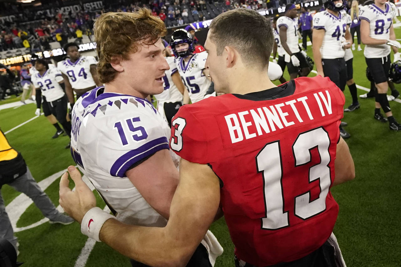 Georgia quarterback Stetson Bennett (13) speaks with TCU quarterback Max Duggan (15) after the nati...