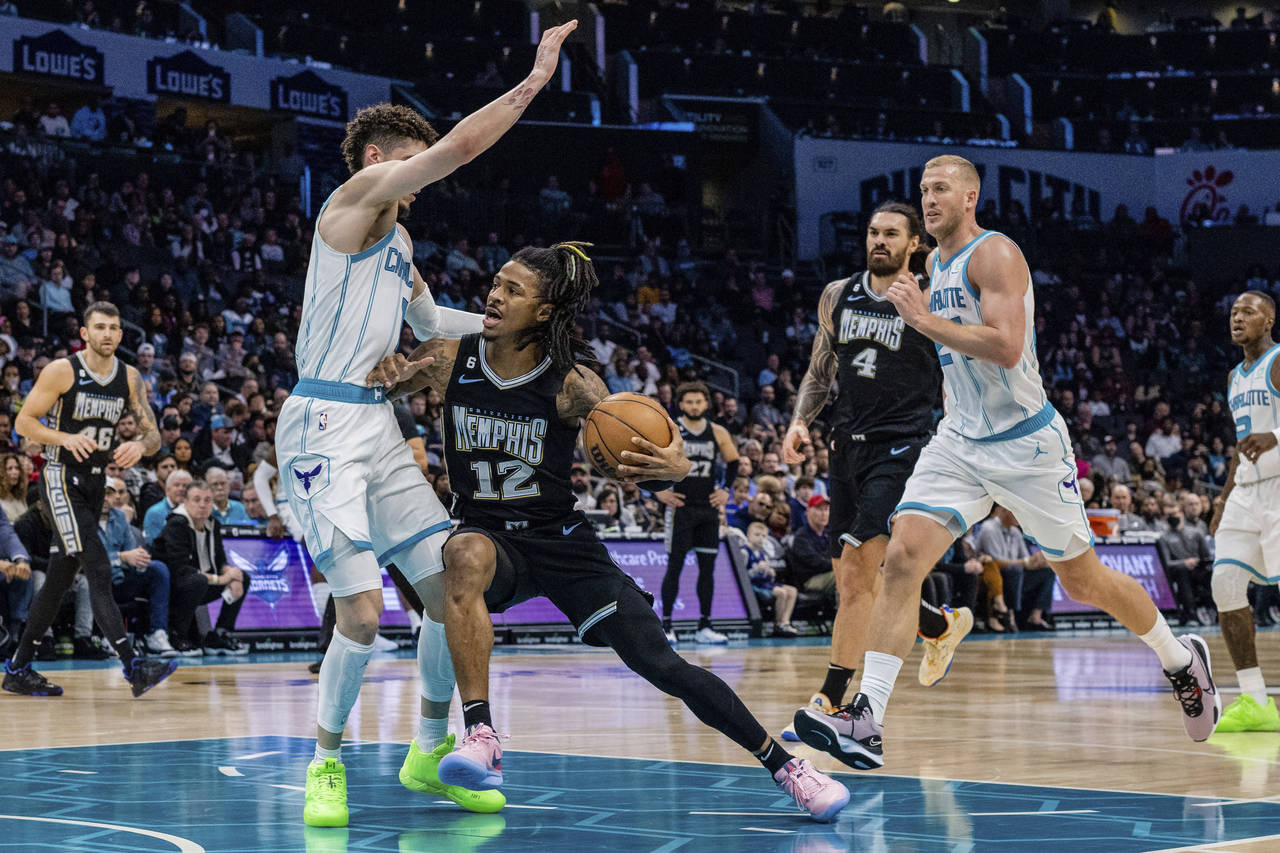Charlotte Hornets guard LaMelo Ball guards Memphis Grizzlies guard Ja Morant (12) as he drives to t...