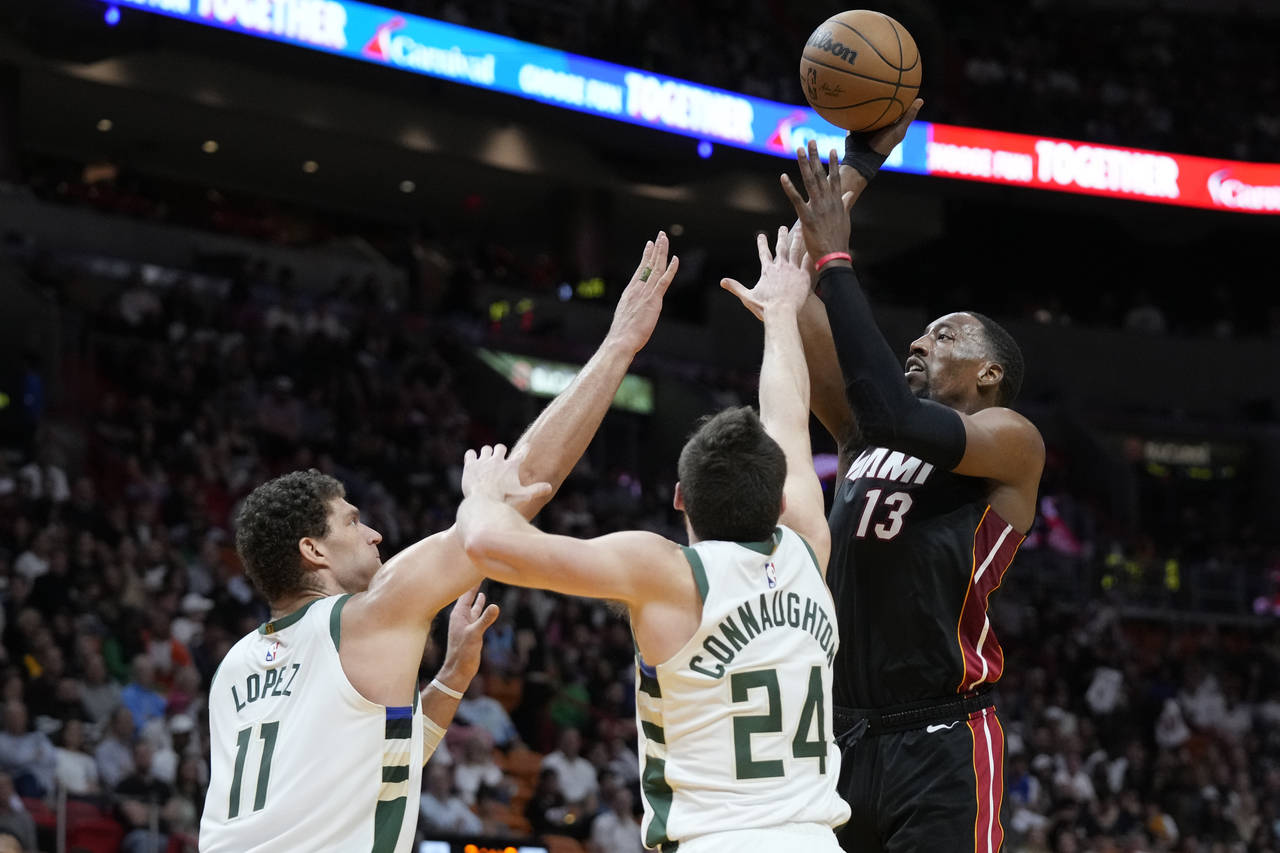 Miami Heat center Bam Adebayo (13) takes a shot against Milwaukee Bucks center Brook Lopez (11) and...