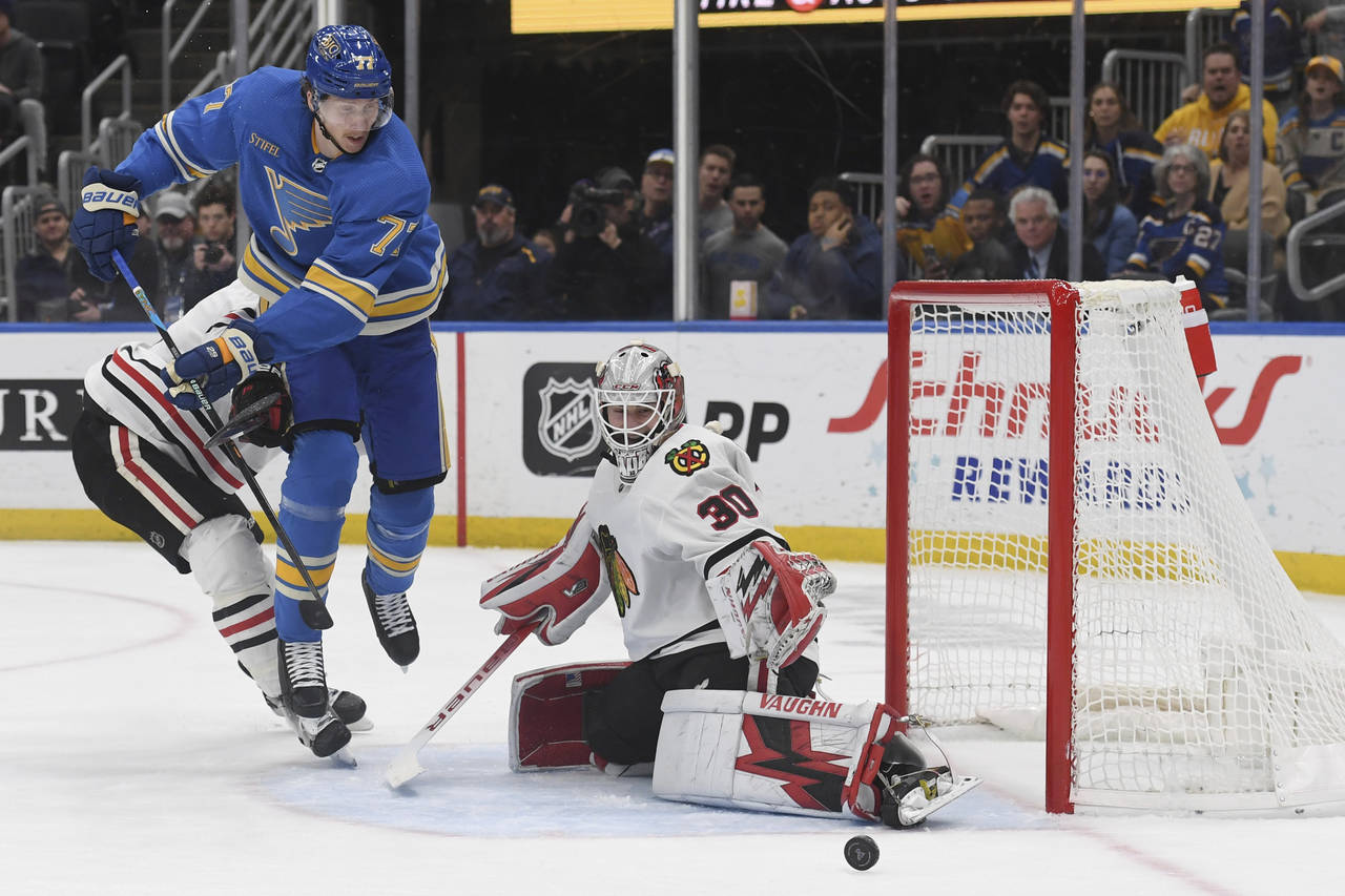 St. Louis Blues' Niko Mikkola (77) attempts a shot against Chicago Blackhawks' Jaxson Stauber (30) ...