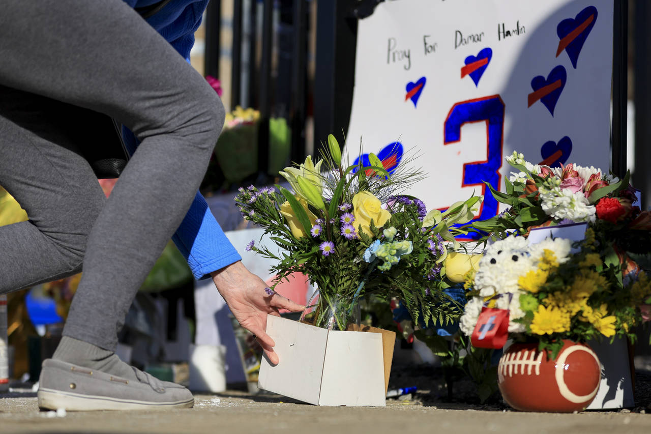 A person leaves flowers for the display set-up for Buffalo Bills' Damar Hamlin outside of Universit...