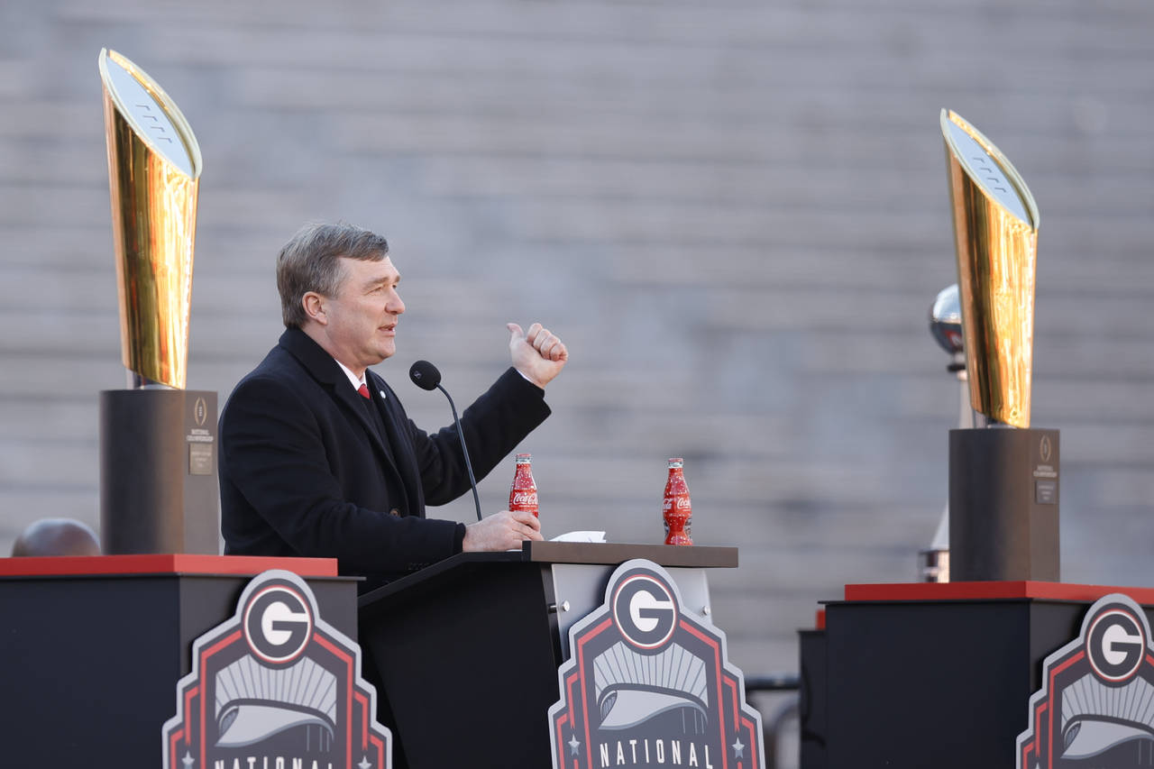 Georgia head coach Kirby Smart speaks while standing between the 2022 and 2023 championship trophie...