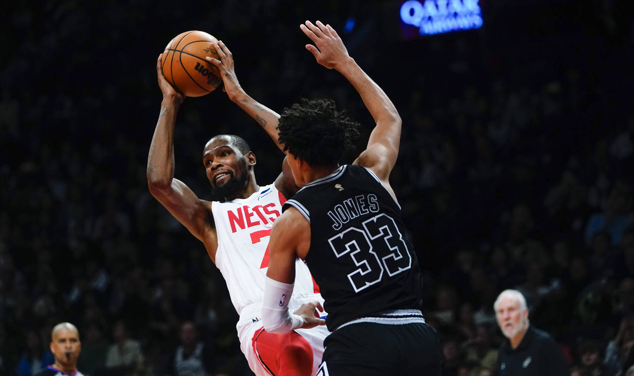 Brooklyn Nets' Kevin Durant, left, protects the ball from San Antonio Spurs' Tre Jones during the s...