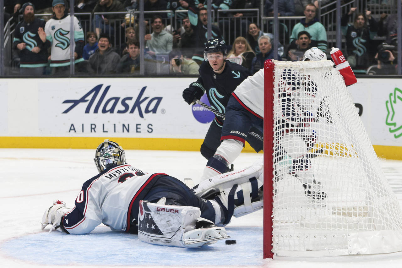 Seattle Kraken center Ryan Donato, rear, watches as the puck rests behind Columbus Blue Jackets goa...