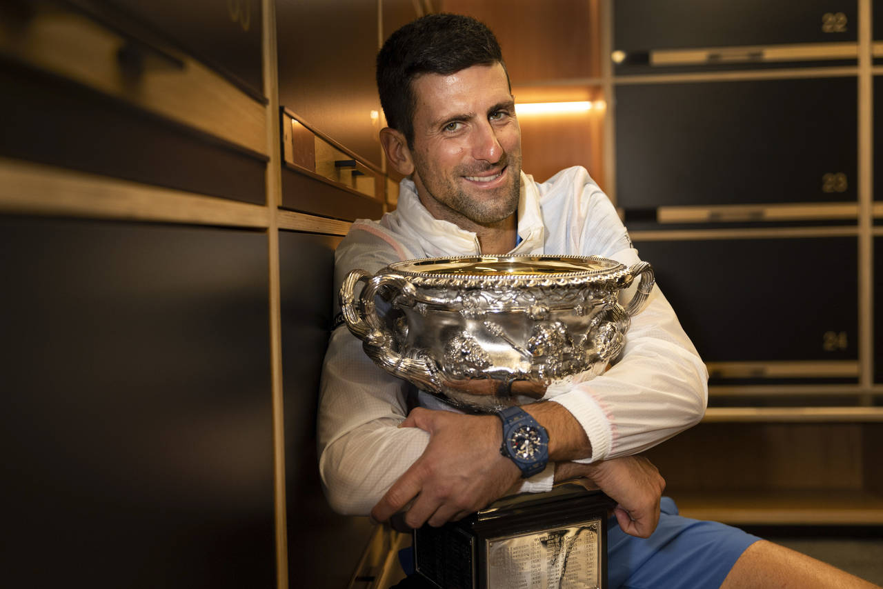 Novak Djokovic of Serbia hugs the Norman Brookes Challenge Cup in the locker-room after defeating S...