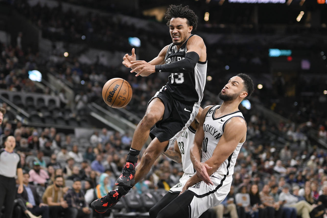 San Antonio Spurs' Tre Jones (33) loses the ball as he collides with Brooklyn Nets' Ben Simmons dur...