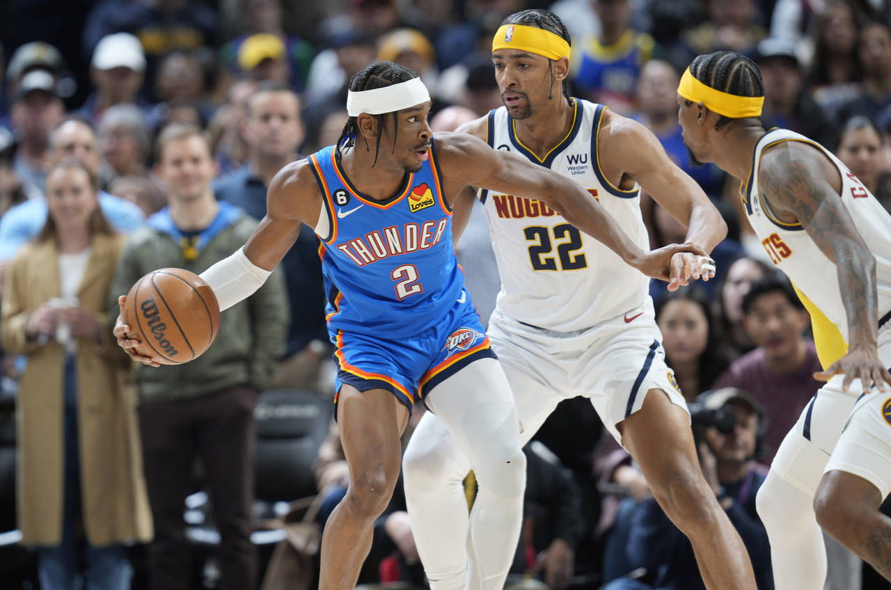 Oklahoma City Thunder guard Shai Gilgeous-Alexander, left, looks to pass the ball as Denver Nuggets...