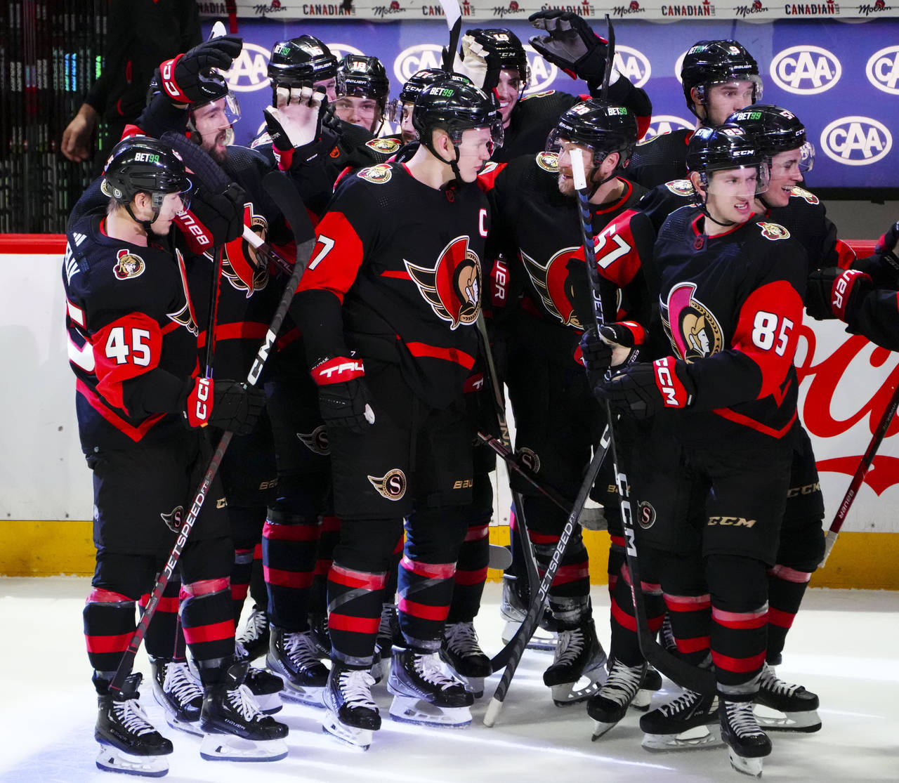 Ottawa Senators crowd around Brady Tkachuk (7) after his overtime goal against the Pittsburgh Pengu...