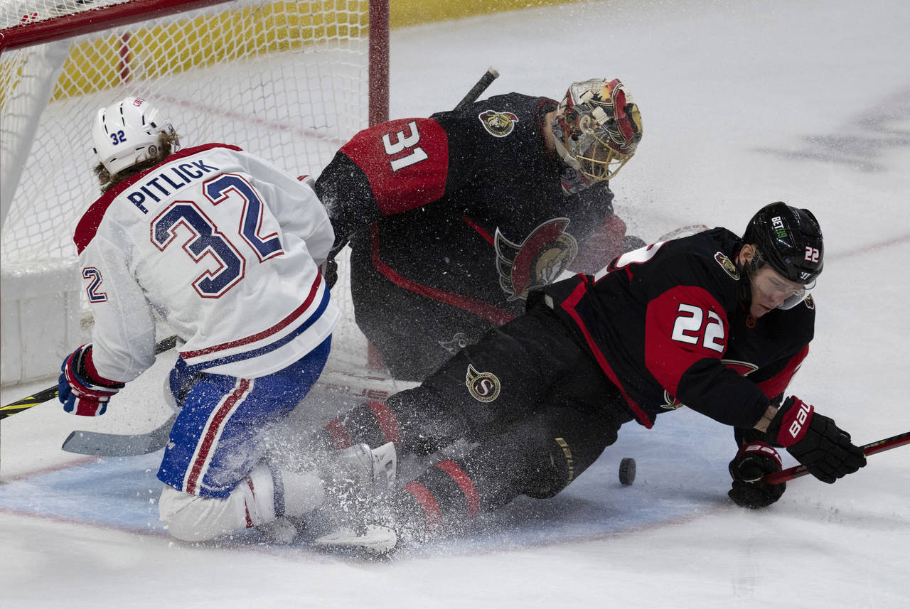 Ottawa Senators goaltender Anton Forsberg, center, watches for the puck as Senators defenseman Niki...