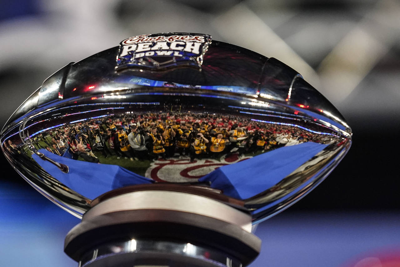 Photographers are reflected in the The George P. Crumbley Trophy after the Peach Bowl NCAA college ...