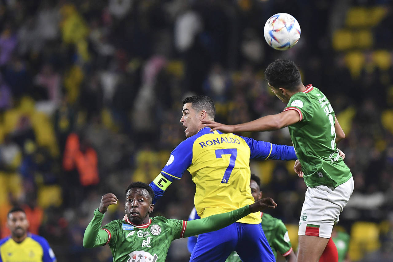 Al Nassr's Cristiano Ronaldo, centre, jumps for the ball against Al Ettifaq's players during the Sa...