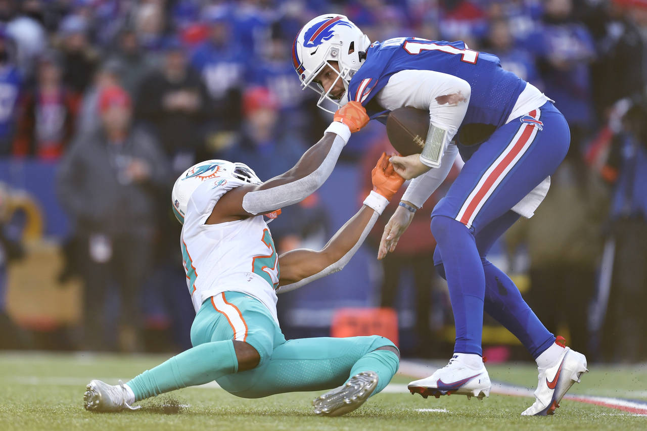 Miami Dolphins safety Eric Rowe (21), left, hangs onto Buffalo Bills quarterback Josh Allen (17) be...