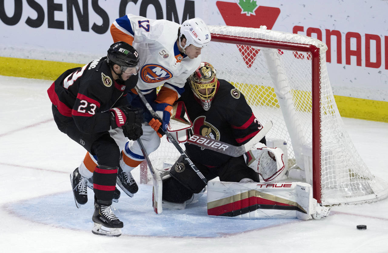 New York Islanders left wing Matt Martin jumps through the crease between Ottawa Senators defensema...