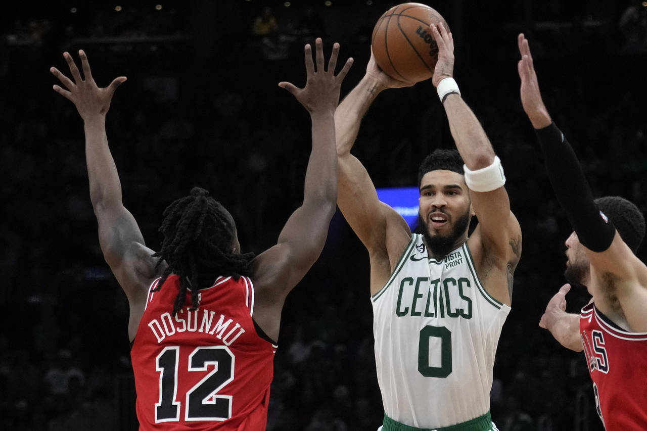 Boston Celtics forward Jayson Tatum (0) looks to pass while pressured by Chicago Bulls guard Ayo Do...