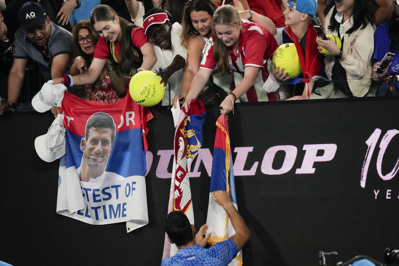 Novak Djokovic of Serbia signs autographs after defeating Roberto Carballes Baena of Spain in their...