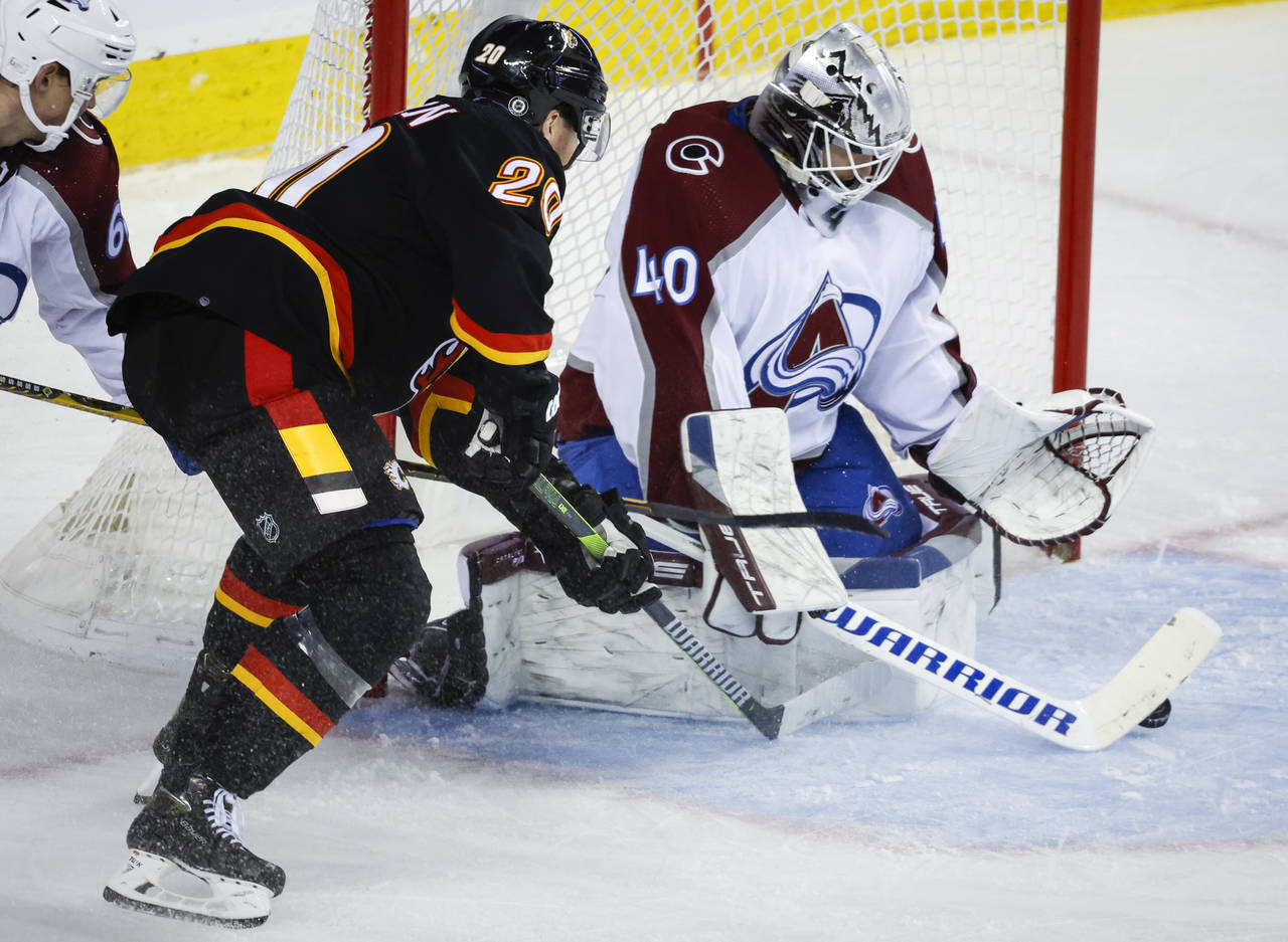 Colorado Avalanche goalie Alexandar Georgiev, right, gets his stick on the puck before Calgary Flam...