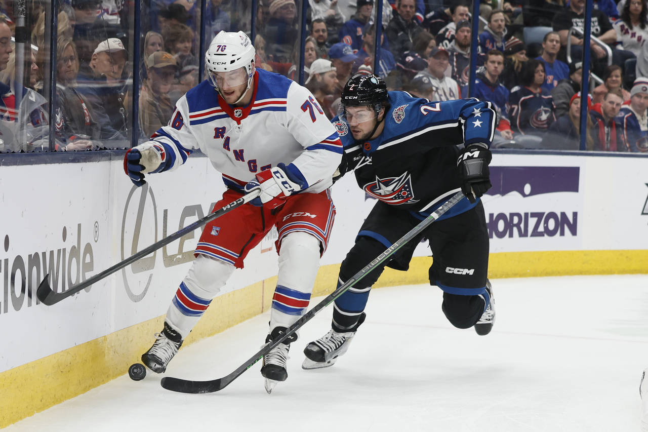 New York Rangers' Jonny Brodzinski, left, and Columbus Blue Jackets' Andrew Peeke chase the puck du...