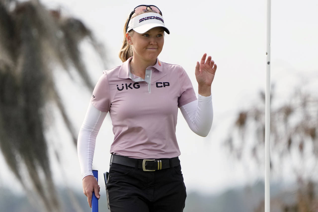 Brook Henderson waves to the gallery after sinking a birdie putt on the 18th green during the first...