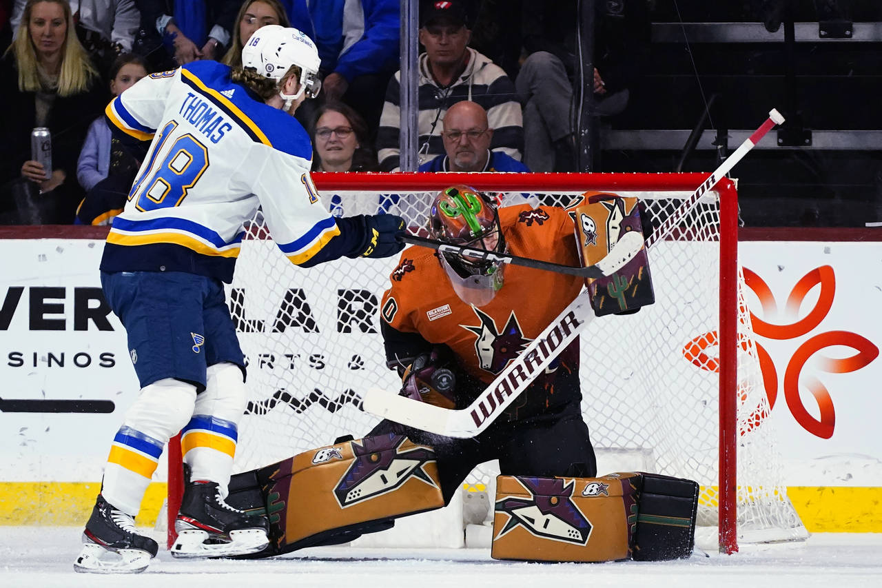 Arizona Coyotes goaltender Karel Vejmelka, right, makes a save on a shot by St. Louis Blues center ...