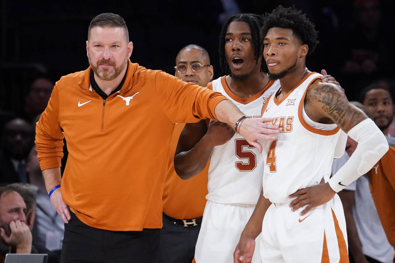 FILE - Texas' head coach Chris Beard, left, meets with Tyrese Hunter (4) and Marcus Carr (5) at the...