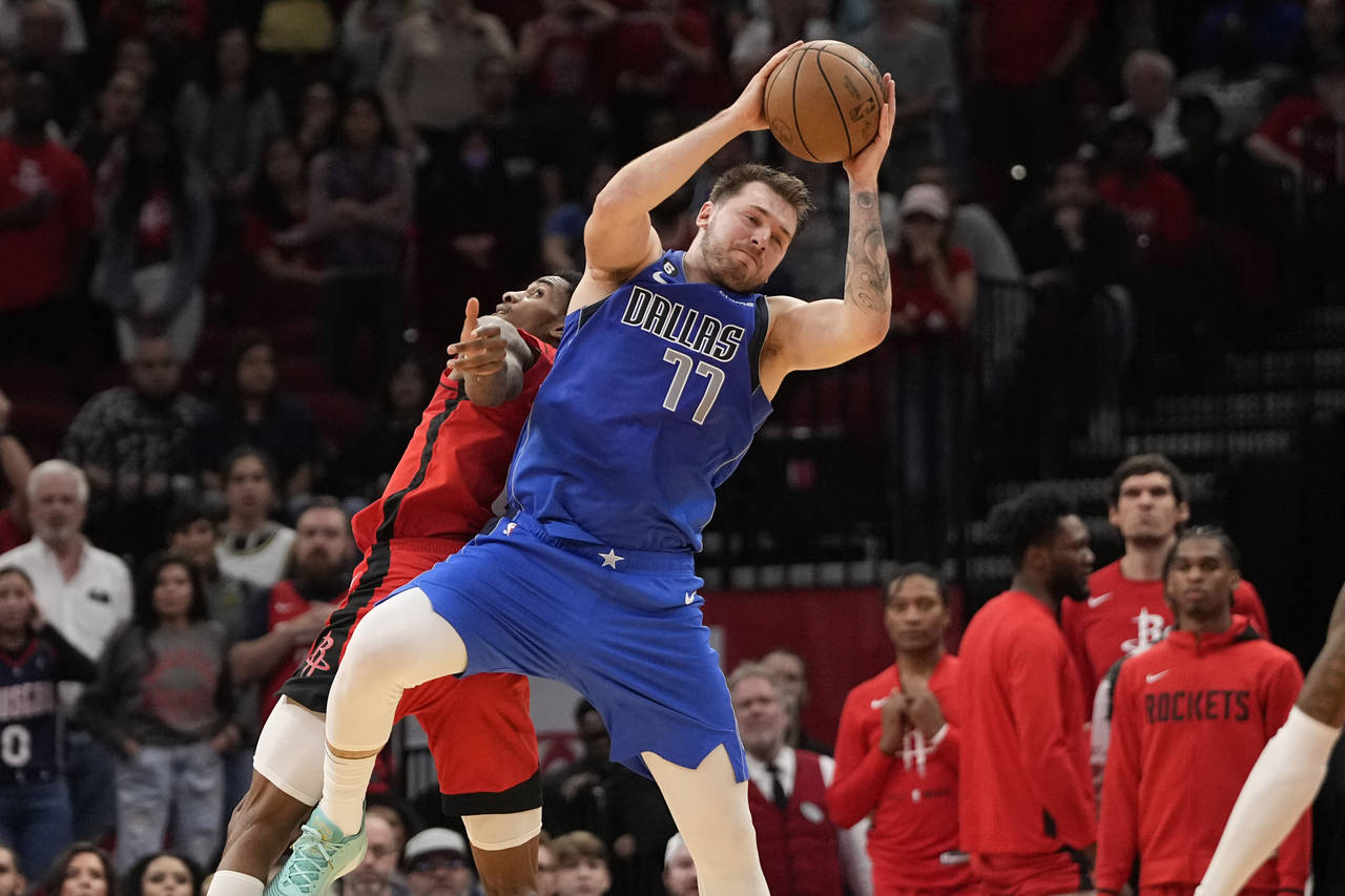 Dallas Mavericks' Luka Doncic (77) grabs in pass as Houston Rockets' Kevin Porter Jr. defends durin...