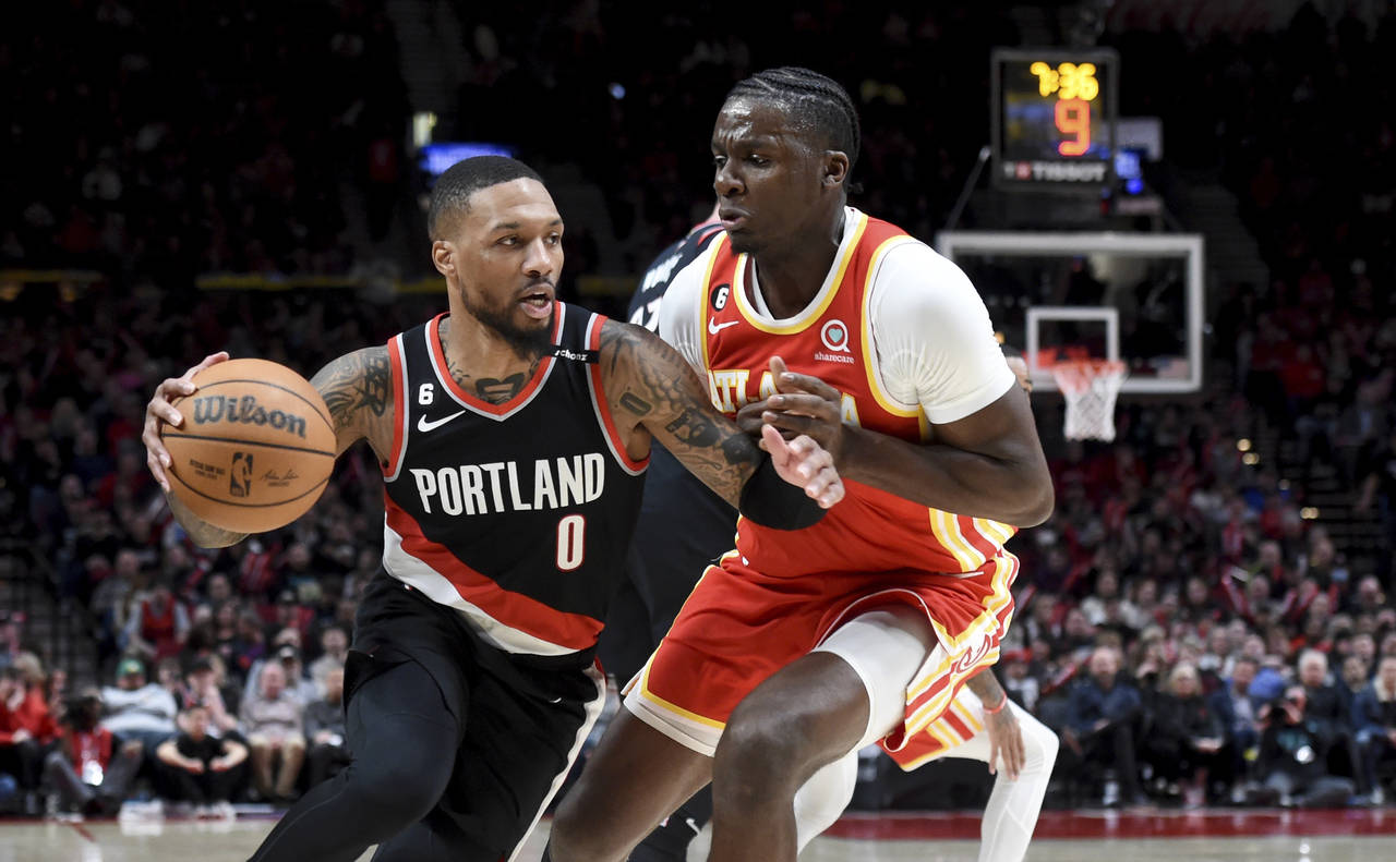 Portland Trail Blazers guard Damian Lillard, left, drives to the basket on Atlanta Hawks center Cli...